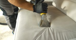 industrial upholstery cleaning showing hands with an upholstery cleaning nozzle on a white couch.
